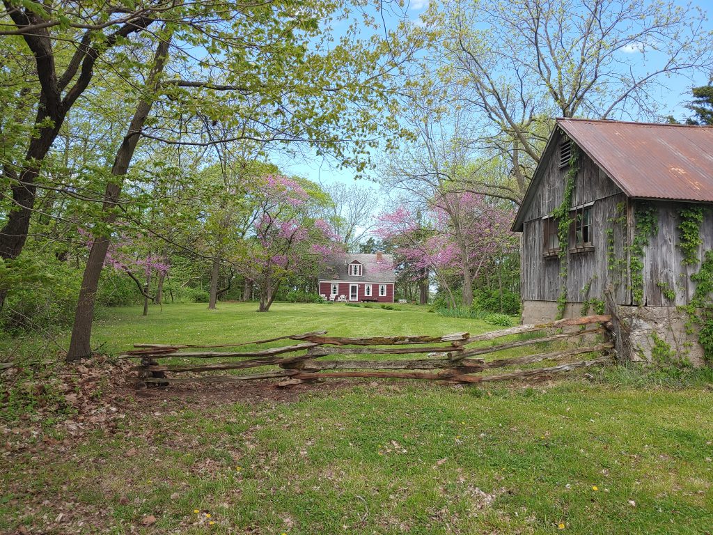small red farm house with split rail fence in front